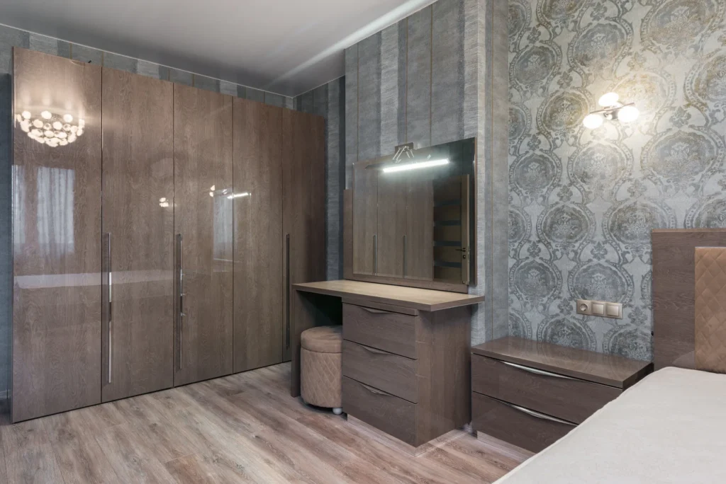 Quarto elegante com móveis planejados em madeira, incluindo armário grande, penteadeira e gaveteiro, destacando-se em harmonia com o papel de parede texturizado.