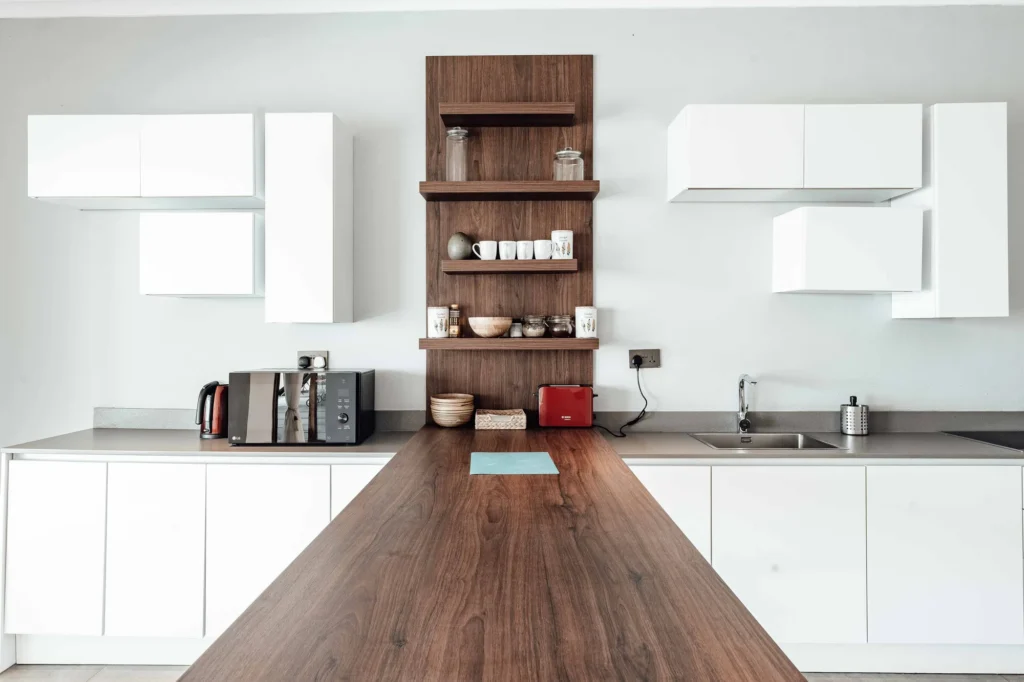 Cozinha moderna com balcão e prateleiras de madeira para móveis planejados, armários brancos suspensos e utensílios de cozinha.